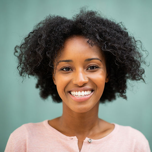 Young Woman Smiling By Green Wall